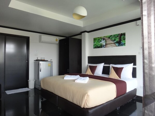 A hotel room with a large bed, a wardrobe, a small refrigerator, and a ceiling light. - Sinsamut Koh Samed Hotel (Rayong)