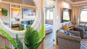 A cozy living room with a large mirror, comfortable seating, a flat-screen TV, and a view of the outdoors.