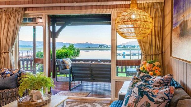 A room with a sofa, a dining table, and a view of a lake.