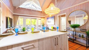 A spacious kitchen with wooden cabinets, a large island with a white countertop, and a hanging light fixture.