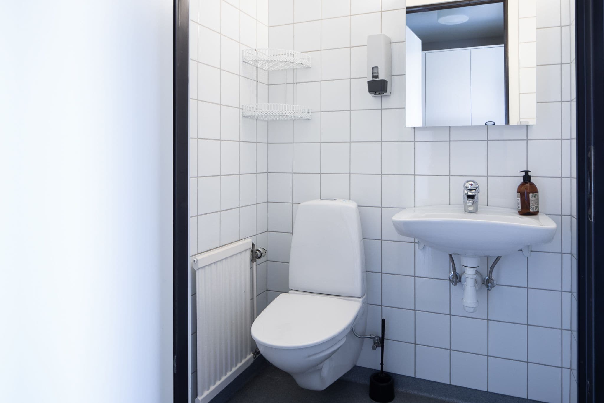 Une petite salle de bain propre, équipée de toilettes, d’un lavabo et d’un miroir.