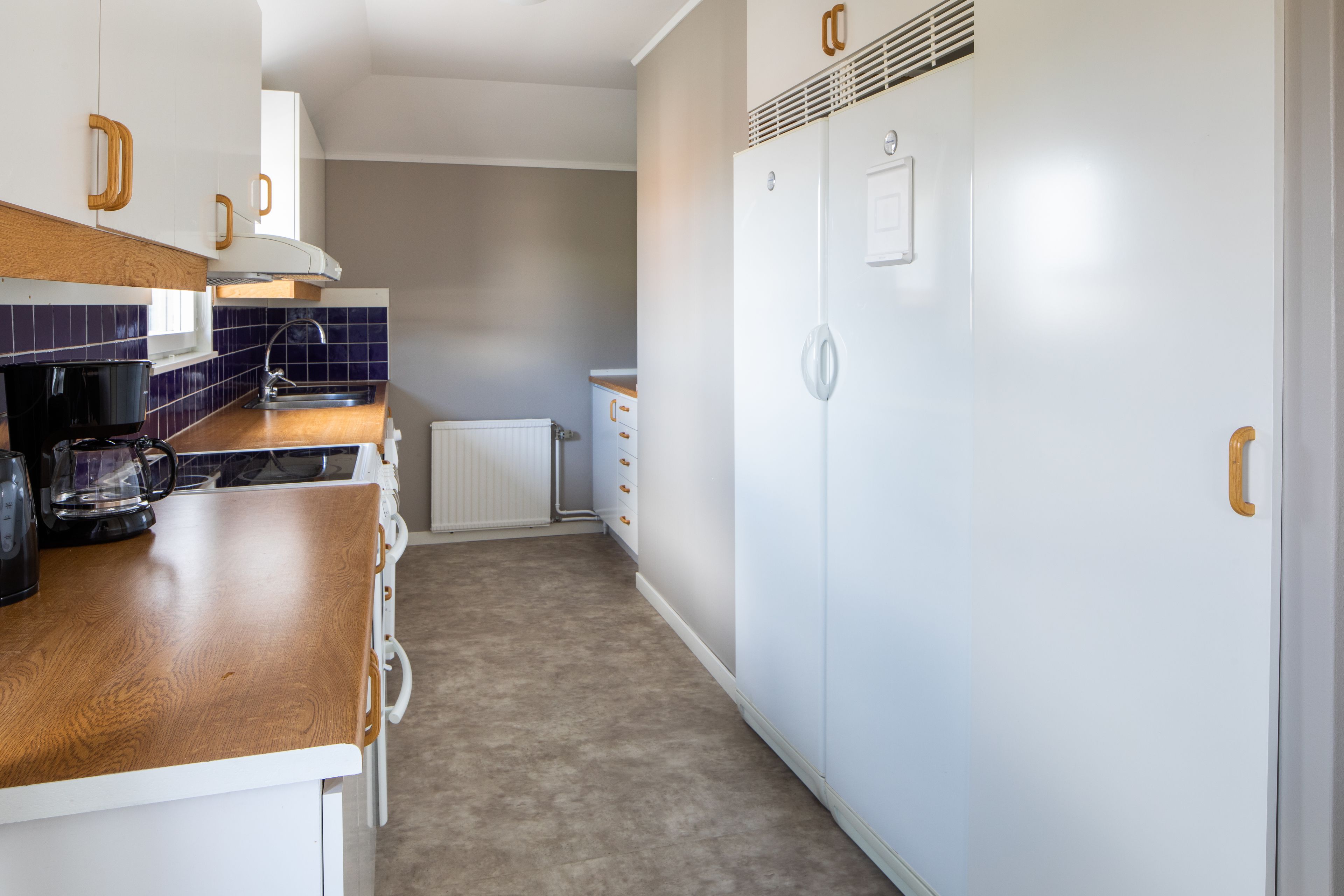 A compact kitchen with a wooden countertop, white cabinets, a built-in oven, and a white refrigerator.