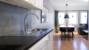Una cocina moderna con un lavamanos de acero inoxidable y un comedor con mesa y sillas.