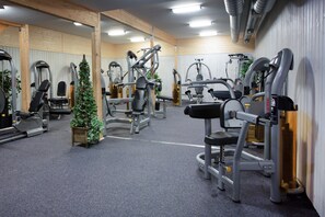 A gym with various exercise machines, wooden beams, and a small potted plant. - Hotel B&B Gränden (Skelleftea)