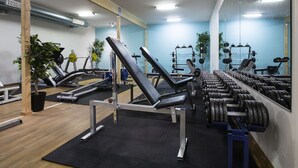 Un gimnasio con equipo de ejercicio, un espejo y plantas.