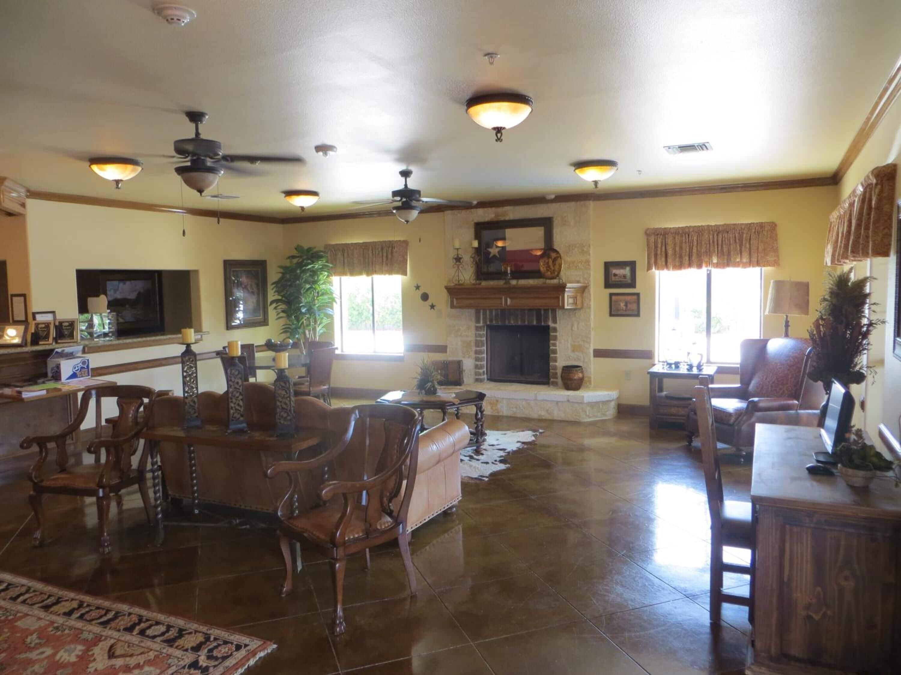Uma sala de estar ampla com lareira, vários ventiladores de teto e diversas opções de assento, incluindo sofás e poltronas de couro.