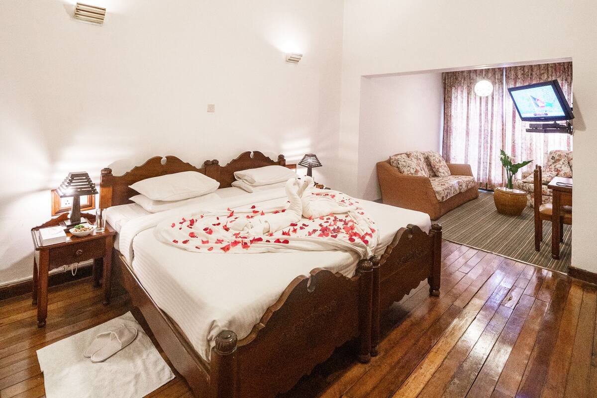Een slaapkamer met een houten bed, een bank, een televisie en een kleine tafel.