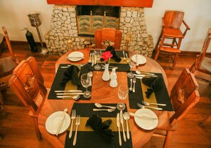 A dining table set for four with a stone fireplace in the background. - Hotel Glendower (Nuwara Eliya)