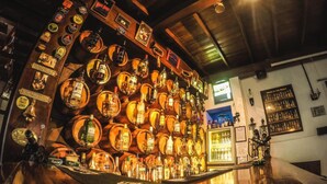 Een bar met talloze flessen en glazen, tentoongesteld op houten planken.