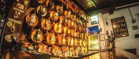Un bar con numerosas botellas y vasos exhibidos en estantes de madera.