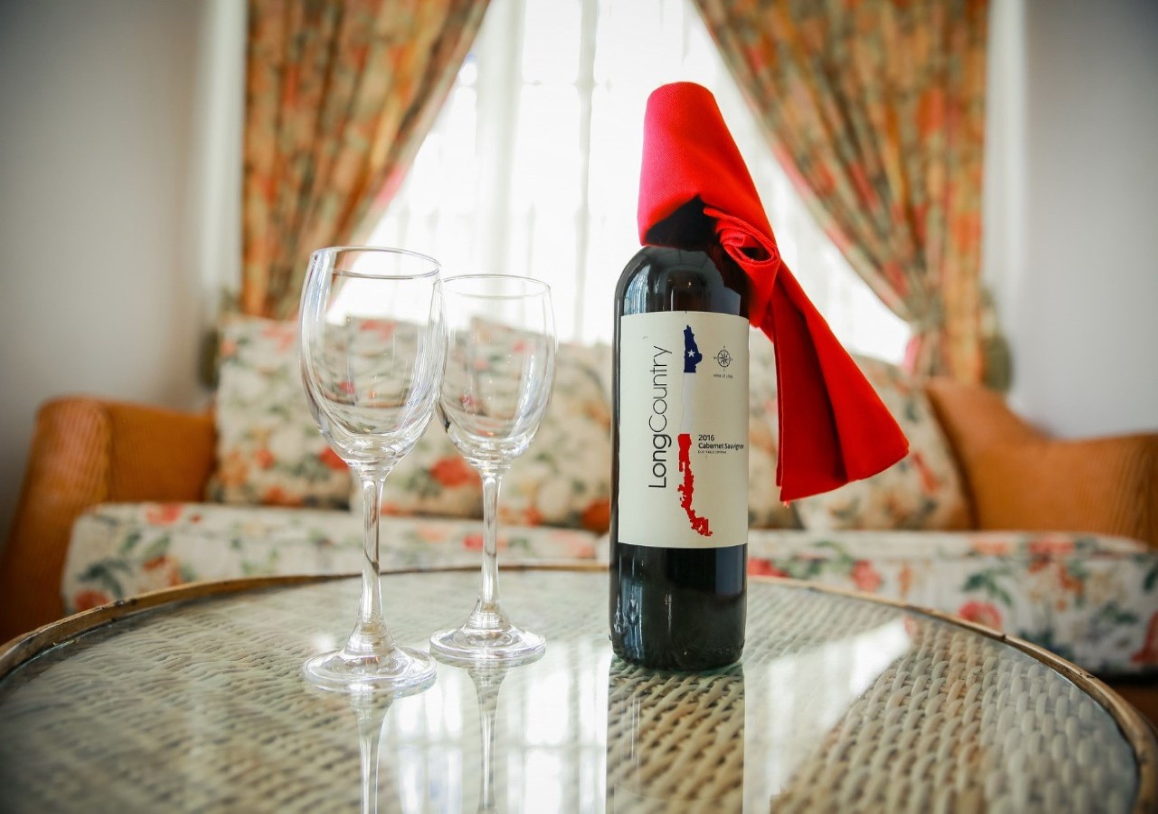 A bottle of Long Country Cabernet Sauvignon on a table with two empty wine glasses.