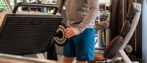 A man using a treadmill in a gym with exercise equipment and a digital display.