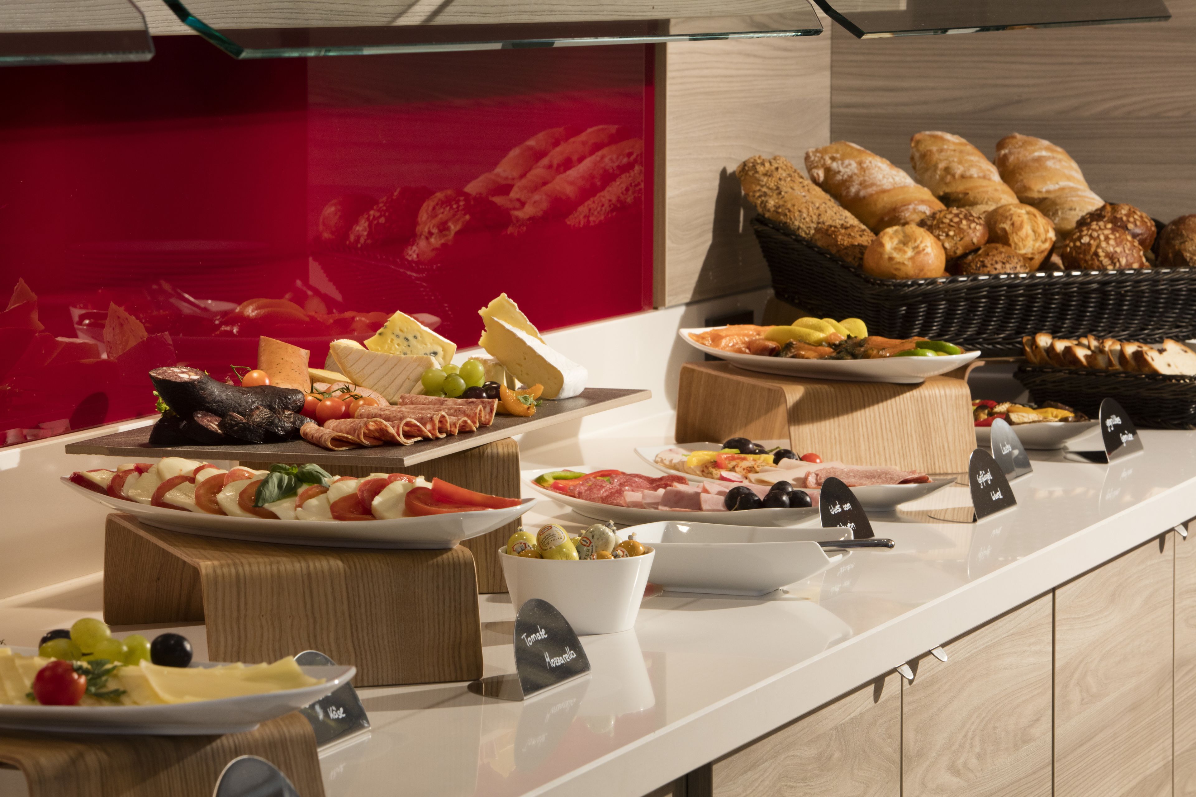 A buffet with various food items including cheeses, meats, and breads.