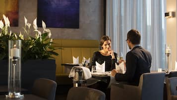 Een eethoek met een tafel gedekt voor twee personen, een bank en een potplant.