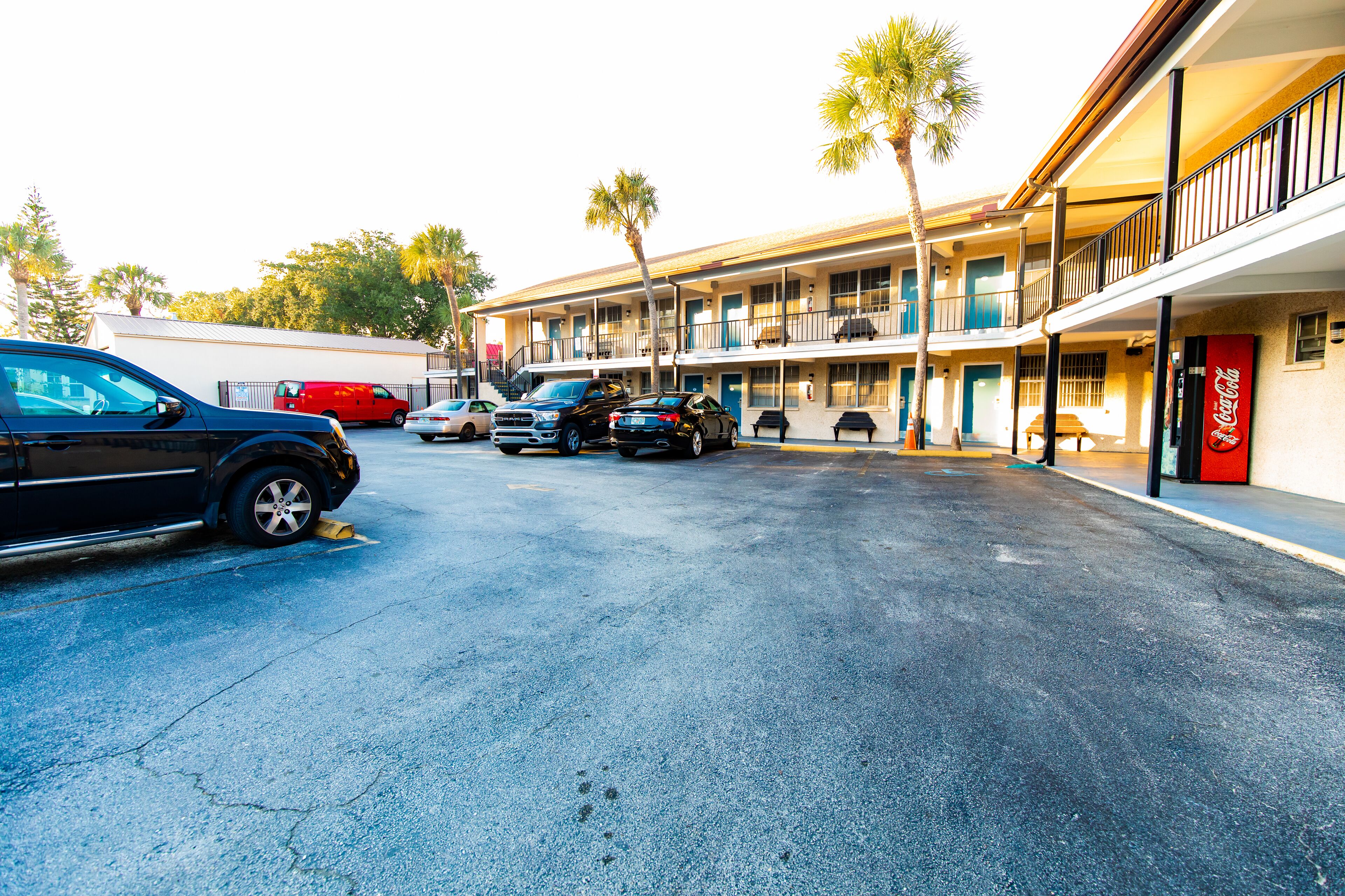 Un motel con varios pisos y balcones, un letrero de Coca-Cola y coches estacionados.