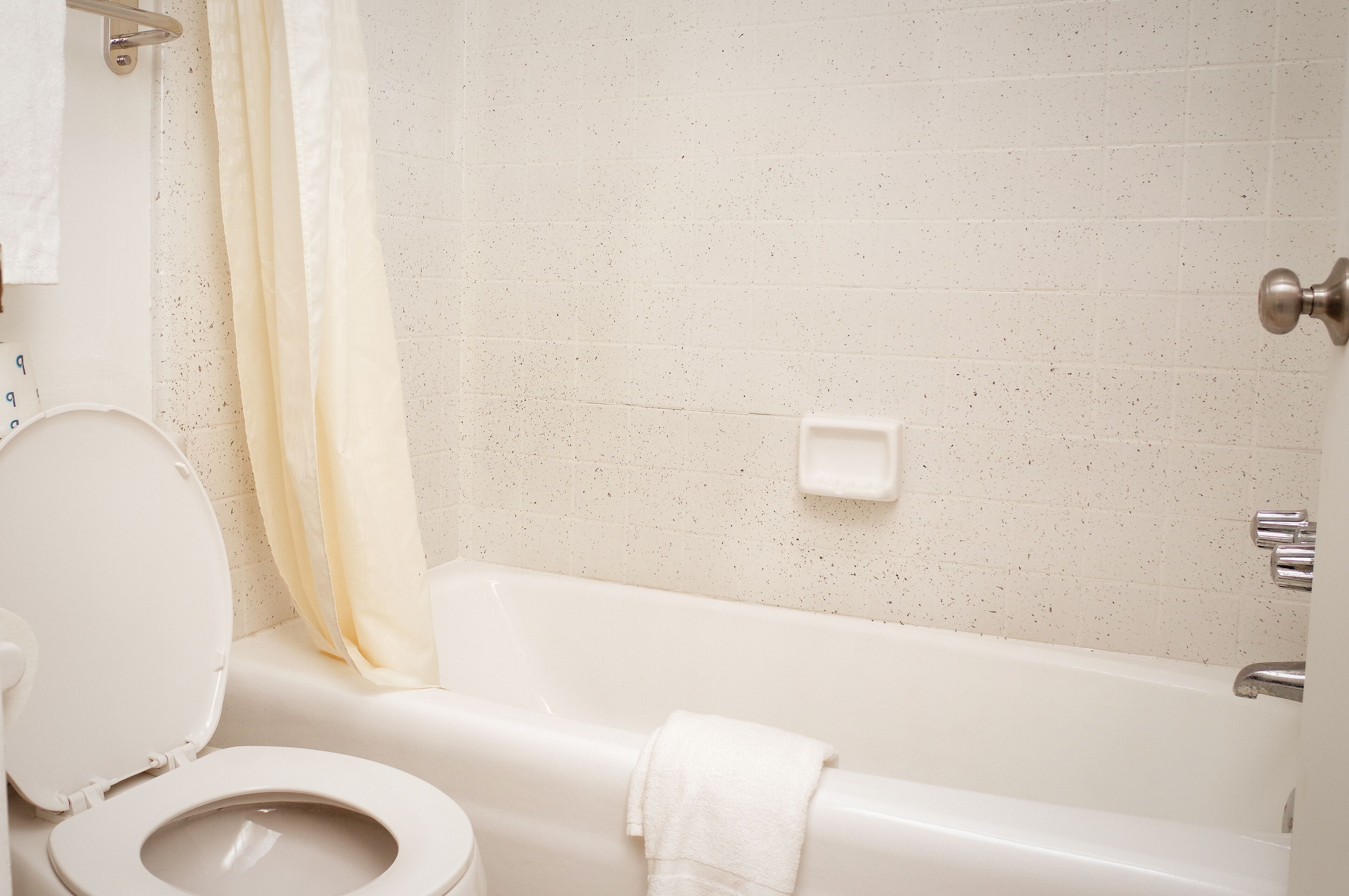 A bathroom with a toilet, bathtub, and shower curtain.