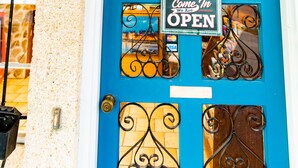 A blue door with a sign that reads "Come In We Are OPEN" and a sign above it that says "OFFICE". - Economy Inn (St. Augustine)