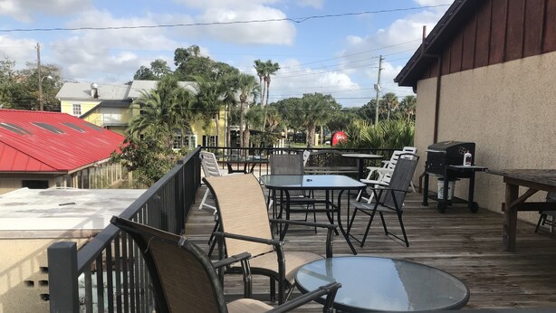An outdoor patio with tables and chairs, a barbecue grill, and a view of the surrounding area including buildings and trees. - Economy Inn (St. Augustine)