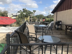 An outdoor patio with tables and chairs, a barbecue grill, and a view of the surrounding area including buildings and trees. - Economy Inn (St. Augustine)