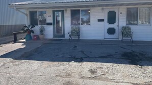 A single-story building with a metal roof, numbered 21, featuring two front windows and a door. - Golden Door Motel (Traer)