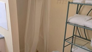 A bathroom with a shower, toilet, and a towel rack. - Golden Door Motel (Traer)