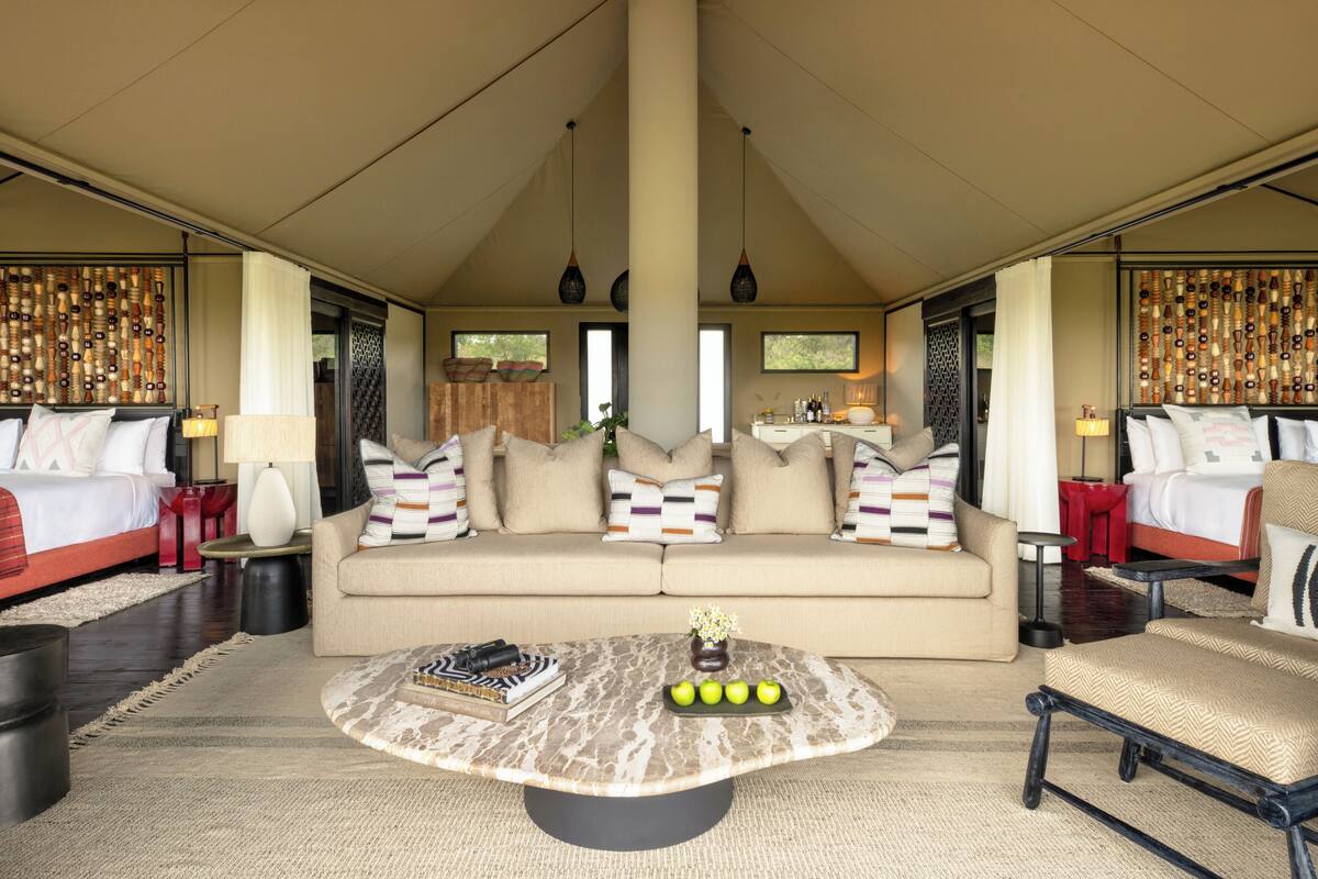 A spacious room with a large sofa, a coffee table, and a bed with multiple pillows.