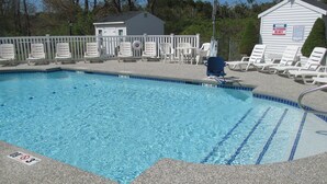 A swimming pool with clear blue water, surrounded by a white fence and lounge chairs. - Long Beach Motor Inn (York Beach)