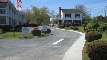 A street view with a building that has a flagpole with the American flag, a speed limit sign, and a sign indicating private property with beach parking.
