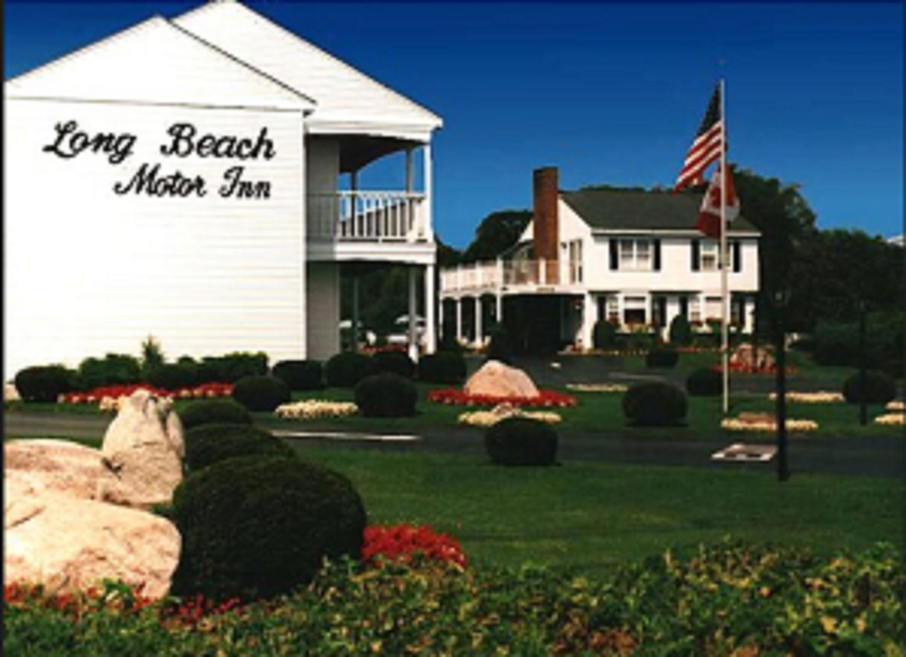 Ein zweistöckiges Gebäude mit einem Balkon und einem Schild mit der Aufschrift 'Long Beach Motor Inn'.