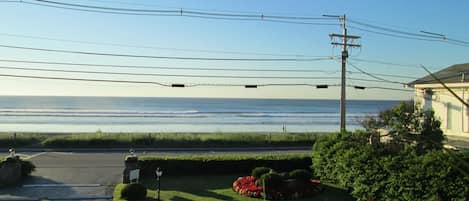 A residential area with a view of the ocean, power lines, and a house with a garden.