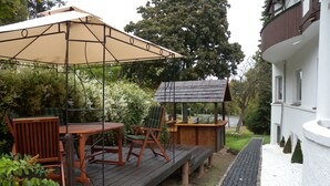 A wooden deck with outdoor furniture, a pergola, and a small wooden structure.