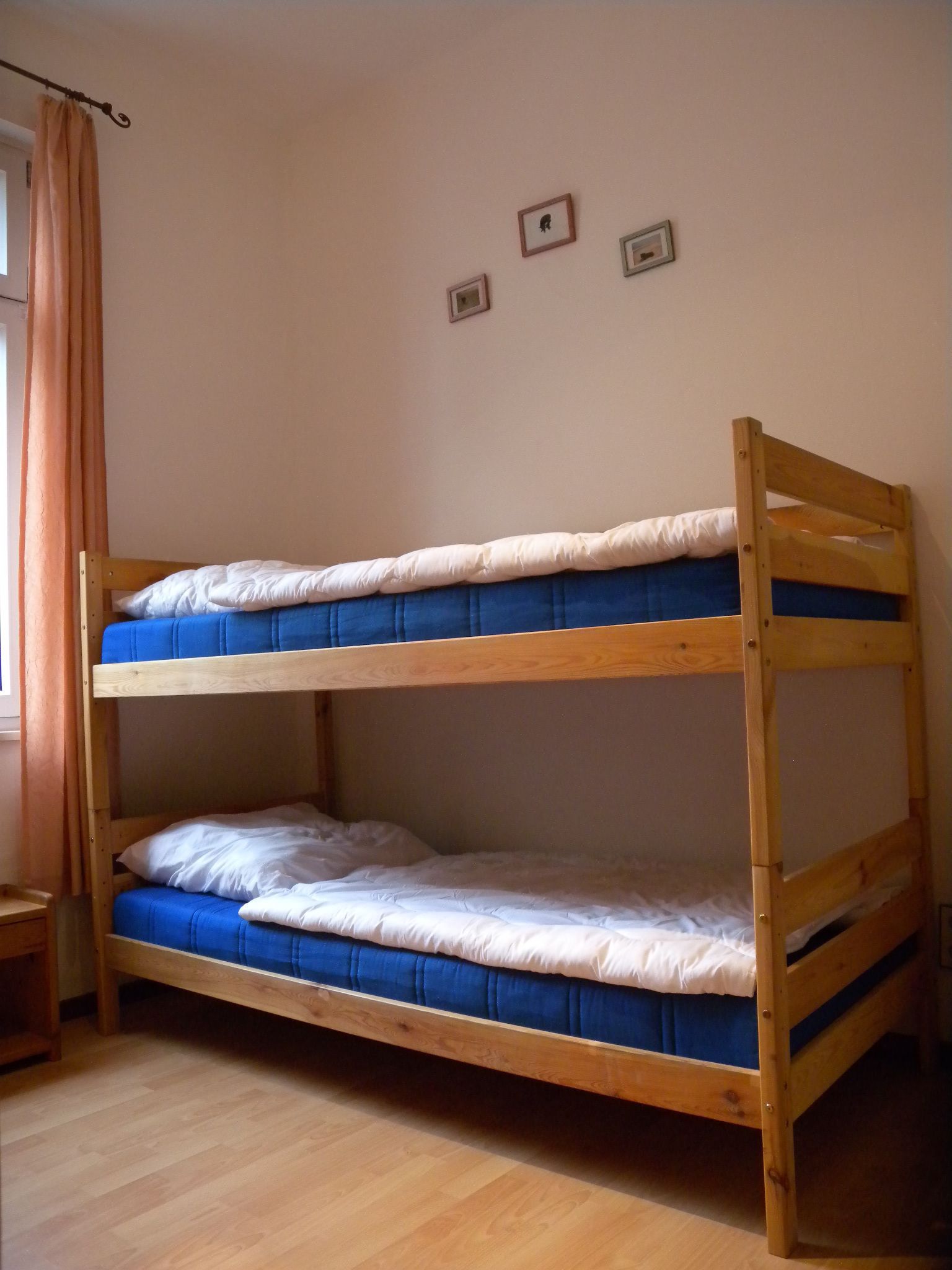 A bunk bed with two levels, wooden frame, and blue bedding.