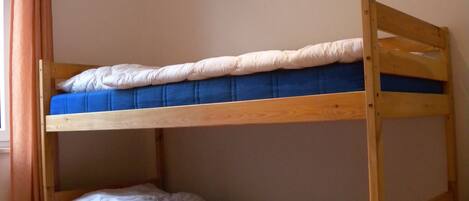 A bunk bed with two levels, wooden frame, and blue bedding.