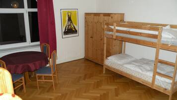 Una habitación con una cama litera, un armario de madera, un escritorio con silla y un cartel en la pared.