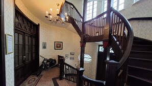 A grand staircase with a wooden handrail and a chandelier, leading to an upper floor.