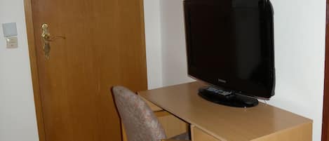 A wooden desk with a television, a chair, and a door with a security keypad.