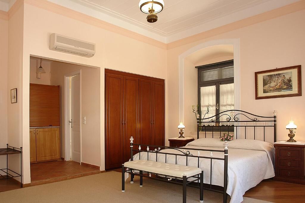 A bedroom with a bed, bedside tables, a bench, a wardrobe, and a window.