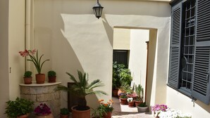 A courtyard with potted plants and a stone bench.