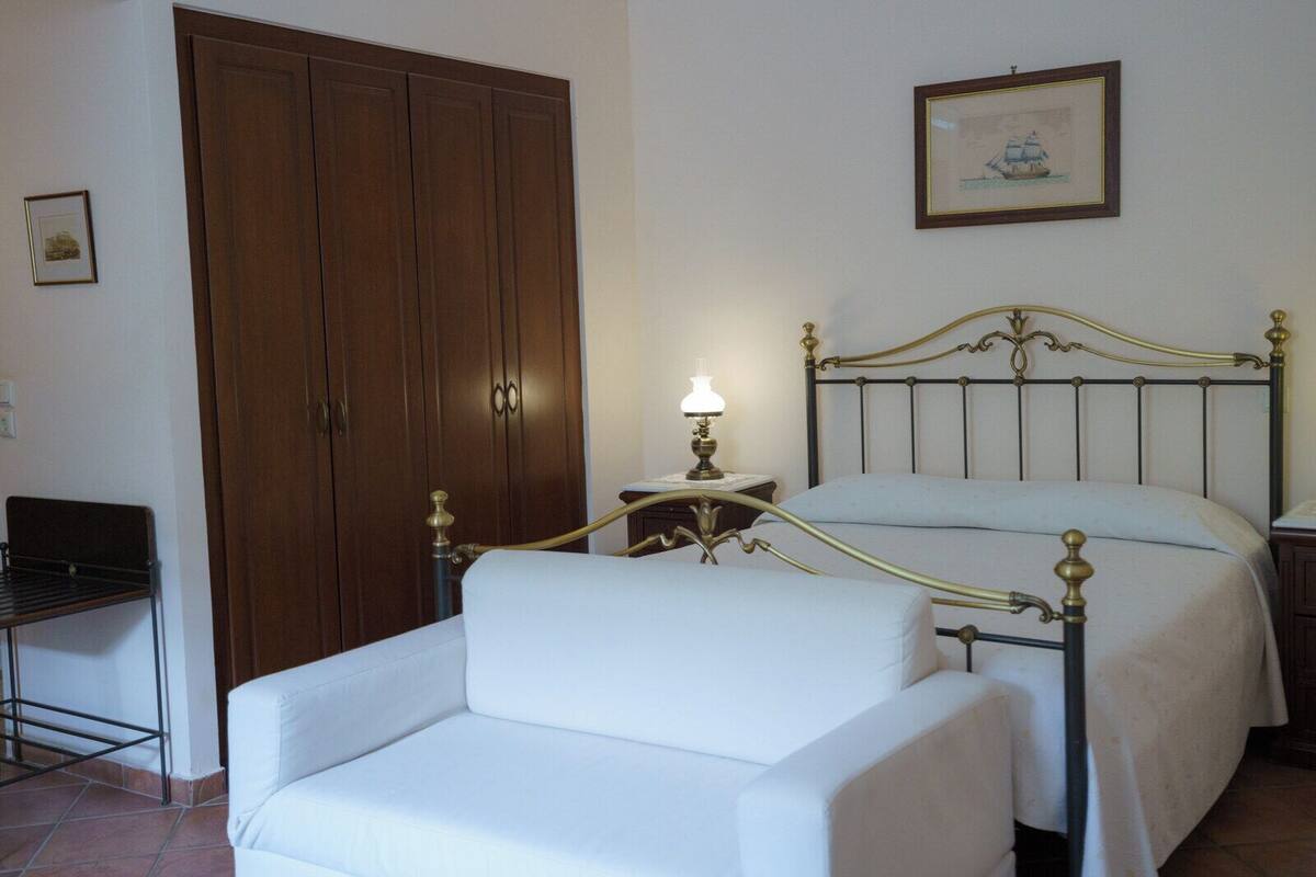 A bedroom with a bed, a bedside table with a lamp, a chair, and a wardrobe.