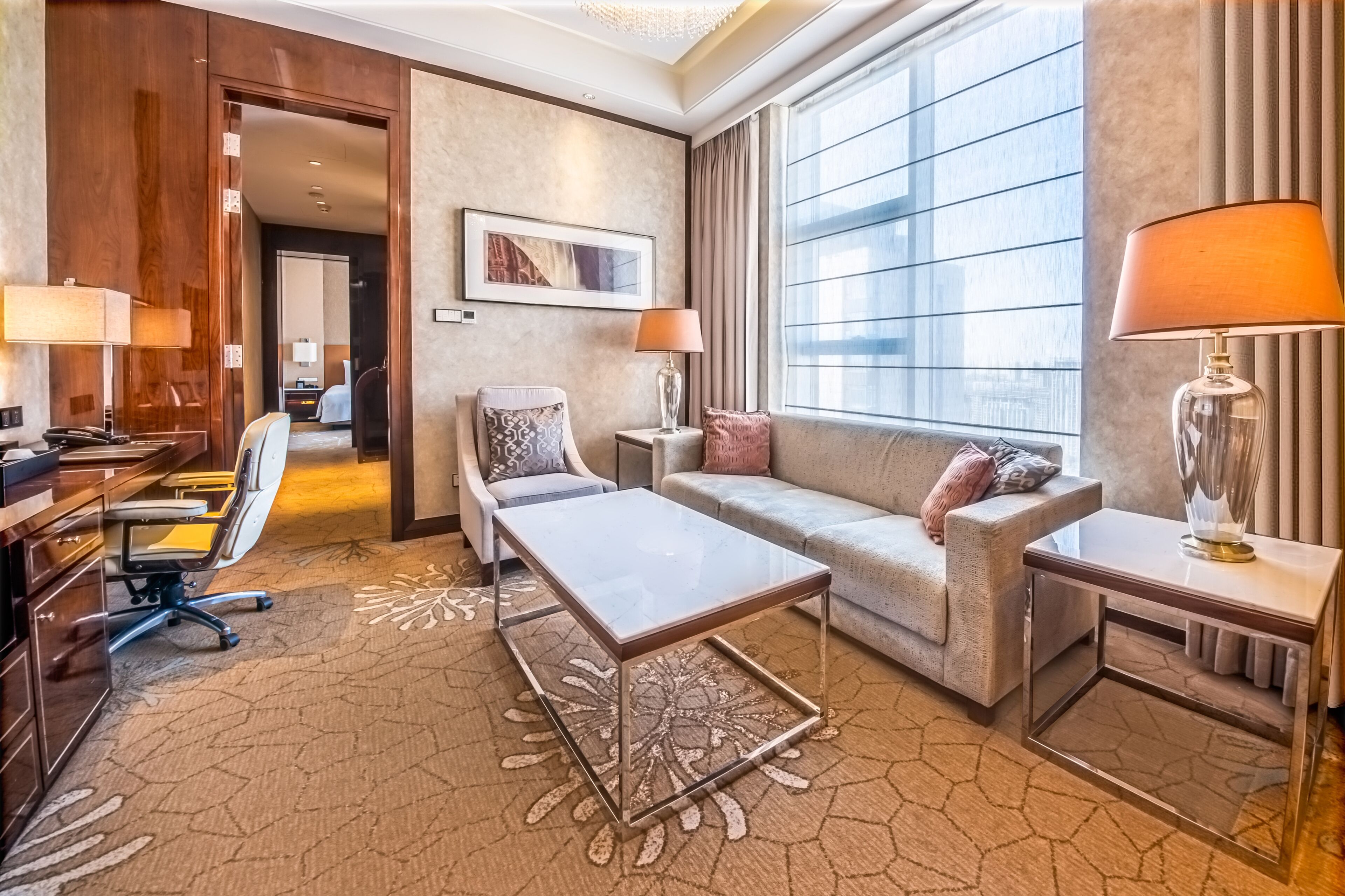 Una habitación de hotel con escritorio, silla, sofá y dos mesitas de noche.