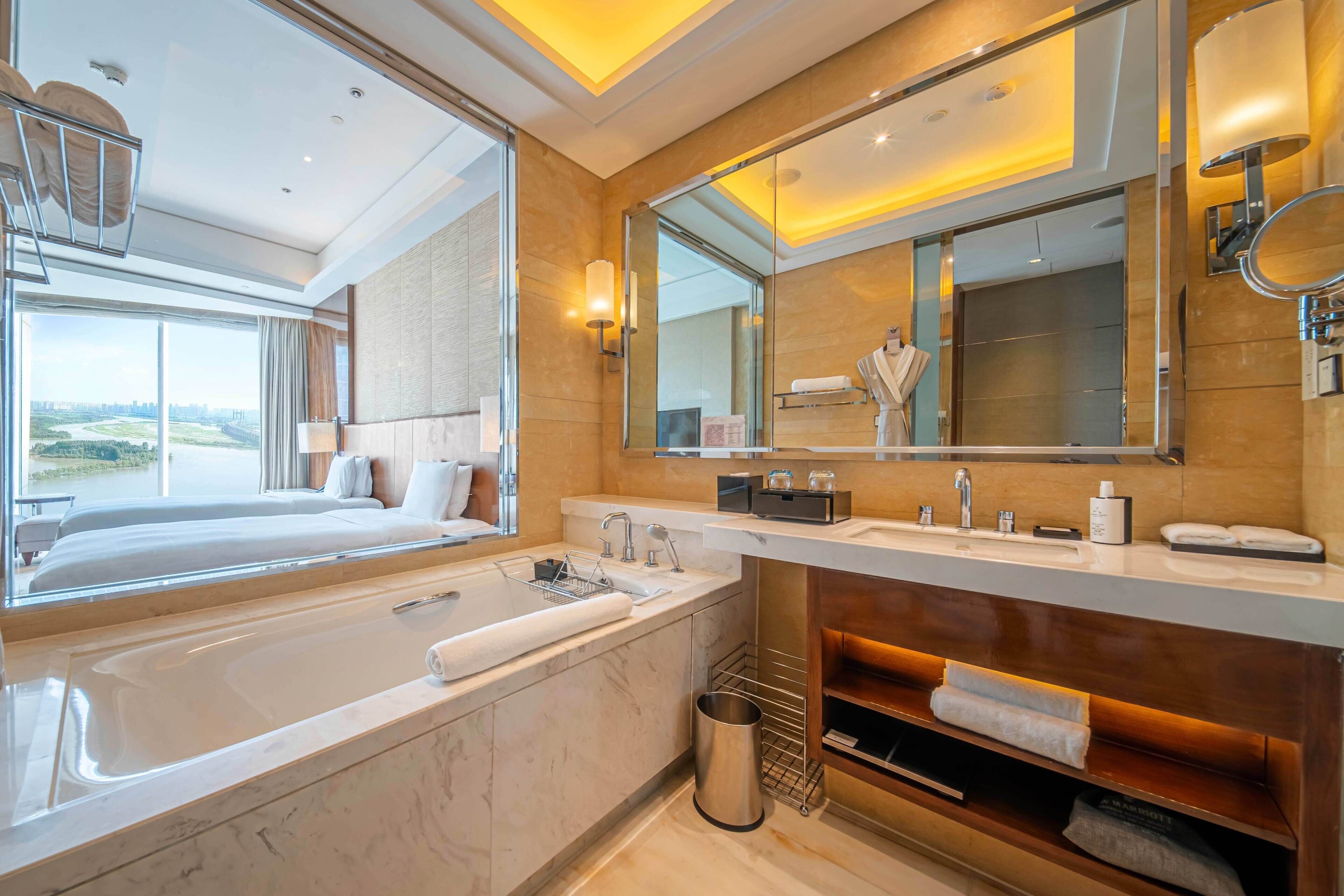 Un baño moderno con una bañera grande, un tocador con espejo y vistas a la ciudad.
