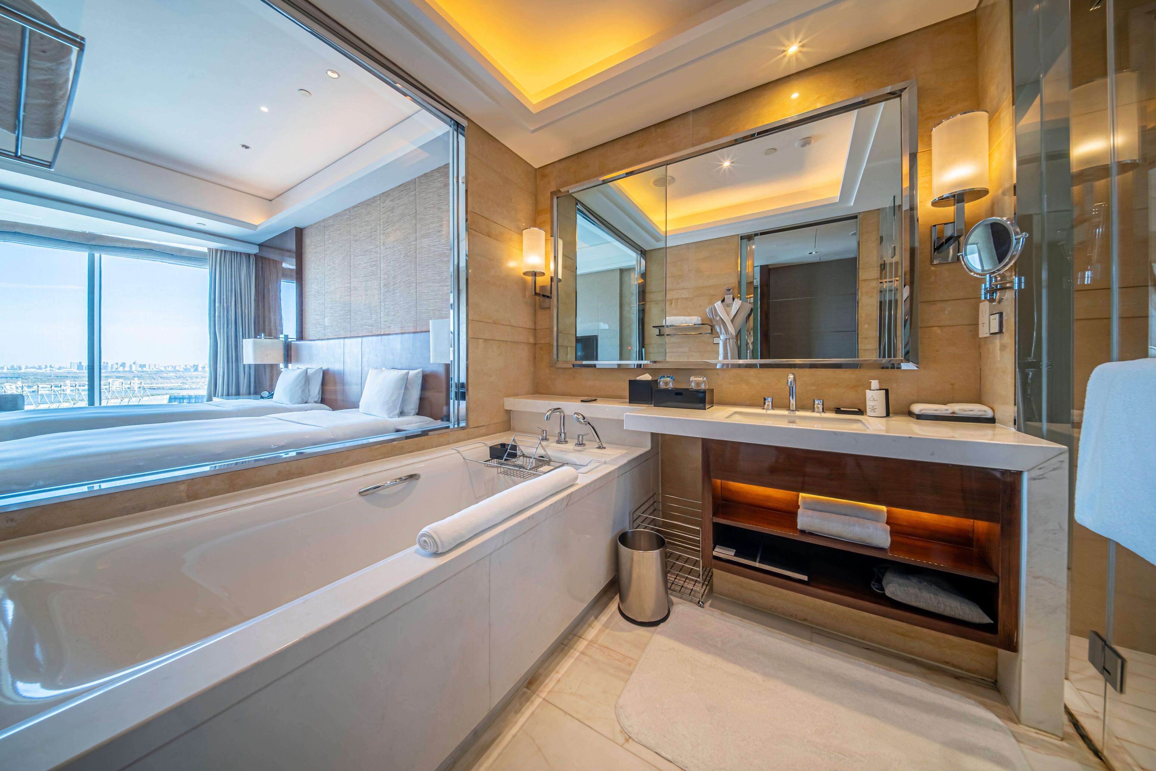 Un baño moderno con una bañera grande, un tocador con espejo y vistas a la ciudad.
