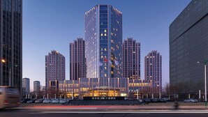 Un hotel moderno con fachada de vidrio, rodeado de edificios altos.