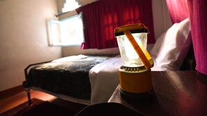 Un lit avec une couette blanche et un rideau rouge, dans une pièce dotée d’une fenêtre.