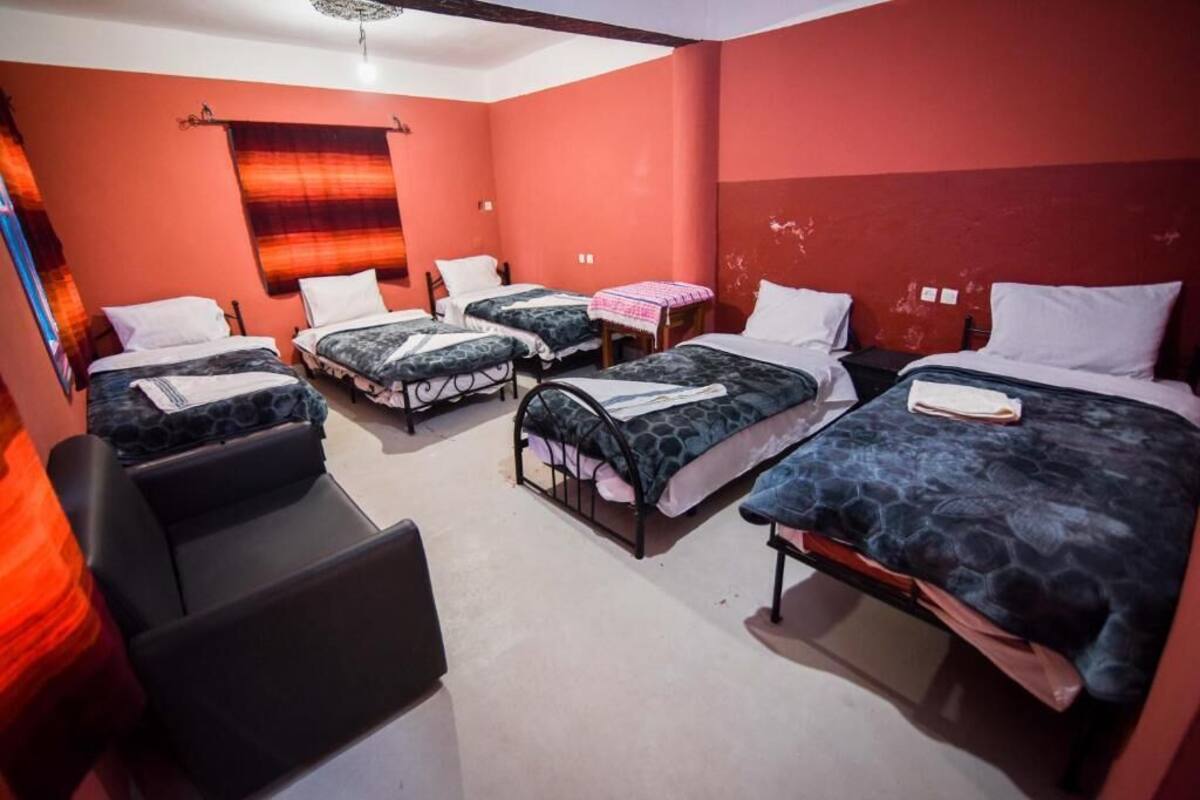 Une chambre de dortoir avec quatre lits, un bureau et une chaise.