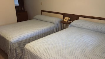 Two twin beds with a textured blue bedspread, a wooden headboard, and a bedside telephone.