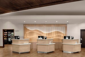 A reception area with three reception desks, a wooden wall with vertical slats, and a 'market' sign on the left.