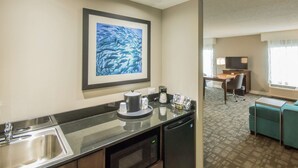 Ein Hotelzimmer mit Küchenzeile, Essbereich, Fernseher und Sofa.