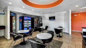 A modern indoor space with vending machines, seating areas, and a television screen.