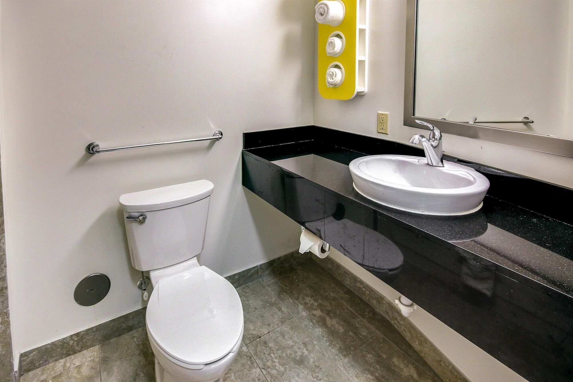 A bathroom with a toilet, a sink, and a mirror.